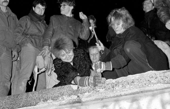 Berliners take a hammer and chisel to a section of the Berlin Wall in front of the Brandenburg Gate after the opening of the East German border was announced in Berlin on 9 November 1989