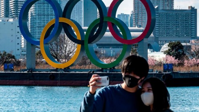 A couple take a selfie in front of the Olympic rings on display at the Odaiba waterfront in Tokyo