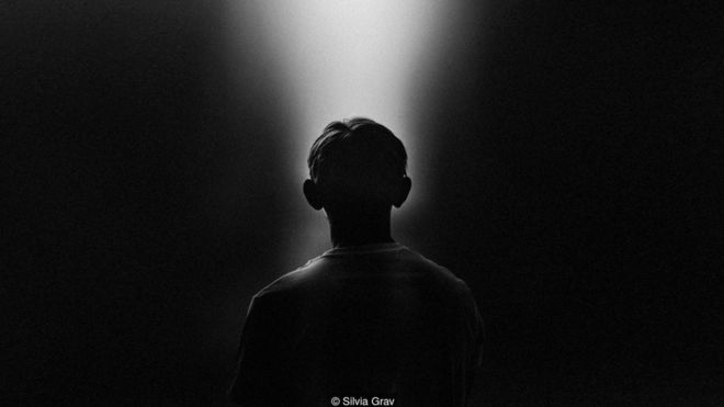 Foto en blanco y negro de una persona mirando una luz. Foto: Silvia Grav.
