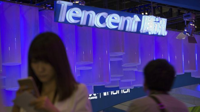 Женщина на смартфоне рядом со стендом Tencent