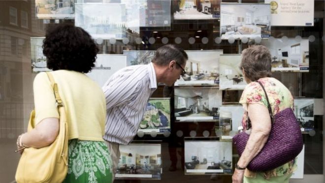 Люди смотрят в окно агента по недвижимости