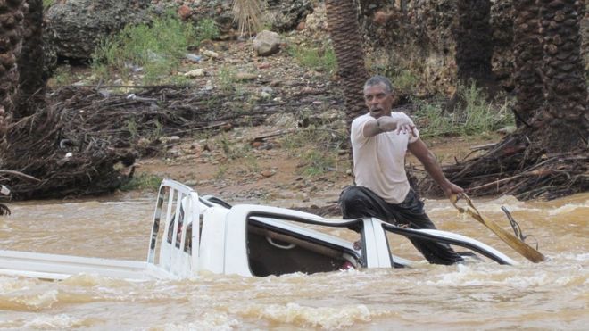 Мужчина пытается спасти автомобиль от того, что его унесут с воды на йеменском острове Сокотра (2 ноября 2015 года)