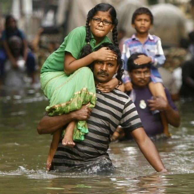 Люди несут детей на своих плечах и пробираются через паводковые воды в Ченнаи, Индия, четверг, 3 декабря 2015 года.