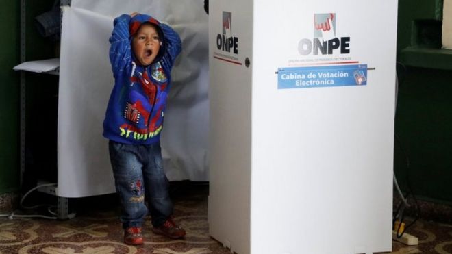 Ребенок зевает, а его мать голосует за кабиной для голосования на президентских выборах в Перу на избирательном участке в Лиме, ??Перу, 5 июня 2016 года.