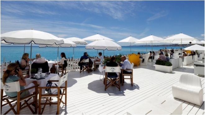 Customers enjoy a lunch on the terrace of a beach restaurant in Nice, France