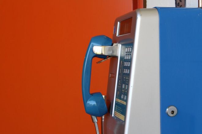 Taipei'de eski bir ankesörlü telefon, parlak kırmızıya boyanmış bir duvar önünde. Telefon temiz ve iyi durumda gözüküyor. Muhtemelen bir süredir hiç kullanan olmadı.