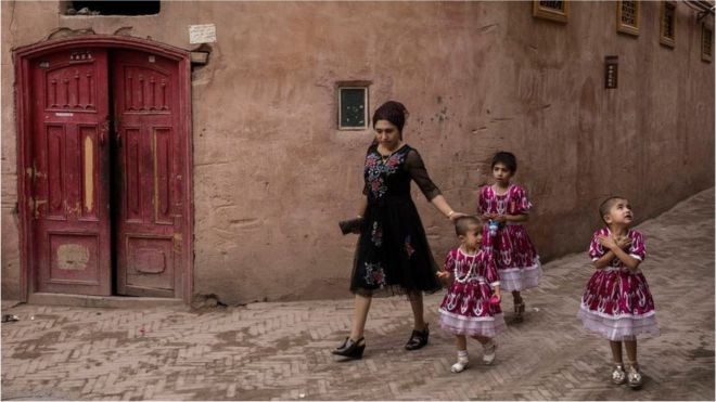 An ethnic Uyghur woman walks with her children on June 28, 2017 in the old town of Kashgar, in the far western Xinjiang province, China.