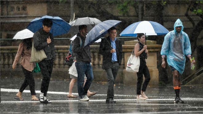 Pedestrians hold umbrellas as they walk in heavy rain in Sydney's central business district on 17 January 2020.