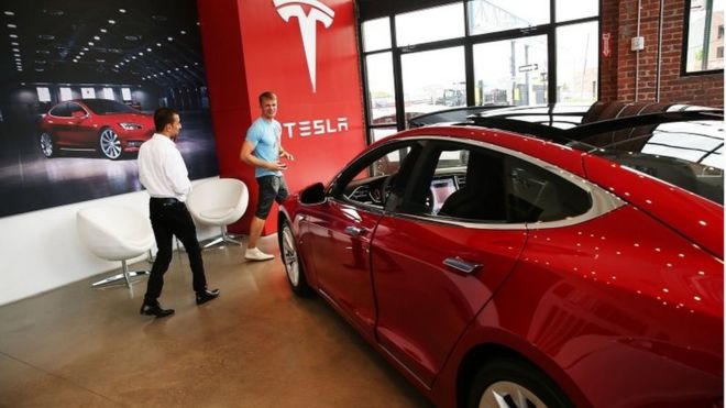 НЬЮ-ЙОРК, NY - 5-ОЕ ИЮЛЯ: Модель s Tesla сидит припаркованный в новом выставочном зале Tesla и сервисном центре в красном крюке, Бруклине 5-ого июля 2016 в Нью-Йорке.