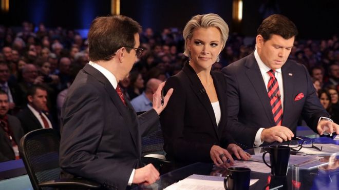 Модераторы Крис Уоллес (слева) похлопывают Мегин Келли (2-я слева), пока они ждут с Бретем Байером (справа) начала президентских дебатов в Fox News