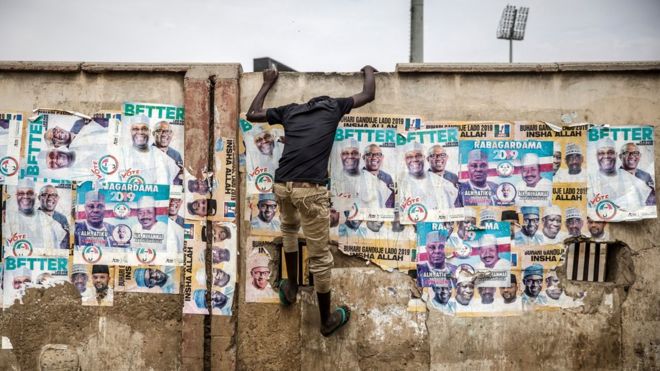 Человек взбирается на стену с предвыборными плакатами