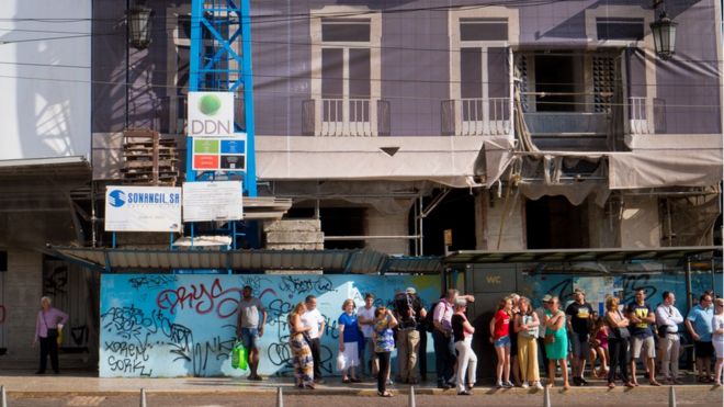 Люди стоят перед отремонтированным зданием в центре Лиссабона