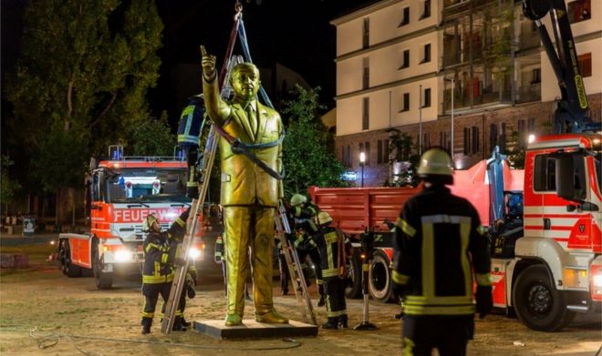 Пожарные поднимают золотую статую с помощью крана под покровом темноты