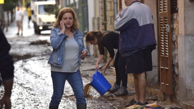Жители убирают воду из своих домов в городе Сан-Льорена на испанском острове Майорка, 10 октября 2018 года
