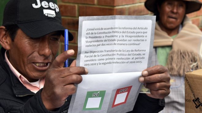 Судья по выборам показывает избирателю бюллетень для голосования 21 февраля 2016 года в Уарине, в 75 км от Ла-Паса, Боливия, во время референдума о конституционной реформе, которая позволила бы Эво Моралесу претендовать на четвертый срок в качестве президента, потенциально продлевая срок его пребывания в должности. до 2025 года