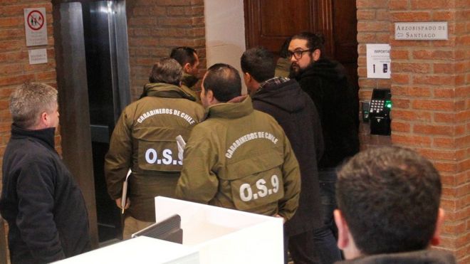 Chilean police officers are seen during the confiscation of the documents inside the office of the Ecclesiastical Court of the archdiocese of Santiago, Chile, June 13, 2018.
