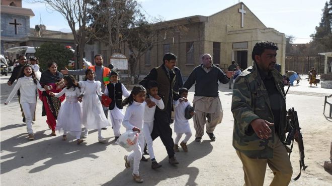 Пакистанские дети-христиане, одетые в белое, эвакуируются сотрудниками службы безопасности из методистской церкви после теракта-смертника во время воскресной службы в Кветте (17 декабря 2017 года)