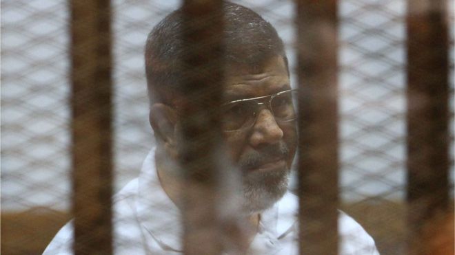 Мухаммед Мурси в клетке обвиняемого во время явки в суд