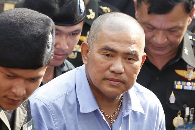 Тайского предполагаемого подозреваемого в том, что он подозревается в том, что подозреваемого в «Лесе-мажете» Сурияна Суджаритполонга (С) сопровождают сотрудники полиции, он прибывает в Военный суд в Бангкоке, Таиланд, 21 октября 2015 года