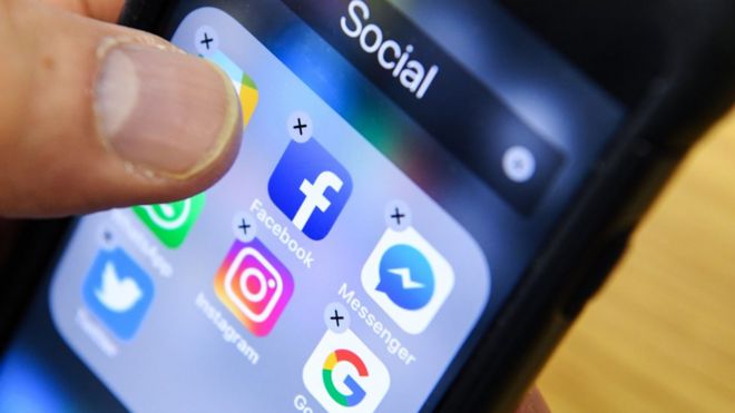 Мужчина держит смартфон со значками для приложений социальных сетей Facebook, Instagram и Twitter