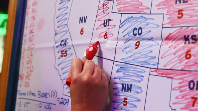 Una persona escribe con un marcador sobre un mapa los resultados de las elecciones en Estados Unidos.