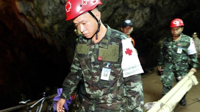 Thai Military Medical personell walk on their their way through a cave during a rescue operation