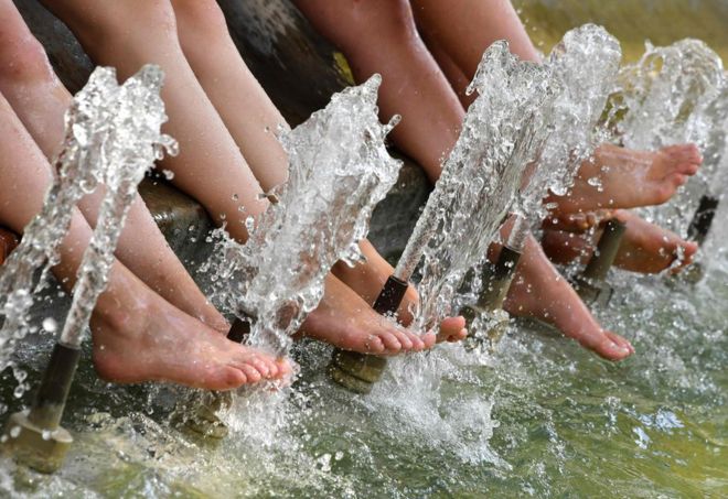 Туристы освежают свои ноги в бассейне во время жары в Монпелье