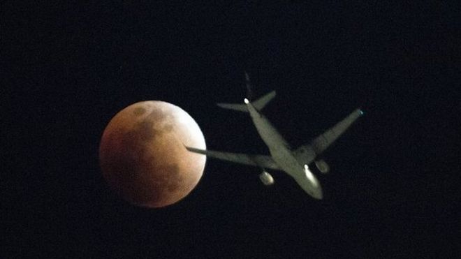 Un avión pasa enfrente de la superluna vista en Hong Kong.