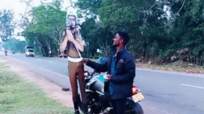 Screen grab from social media video of man bribing life-size cardboard cutout