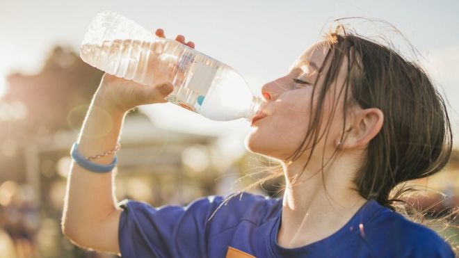 девушка пьет из пластиковой бутылки с водой