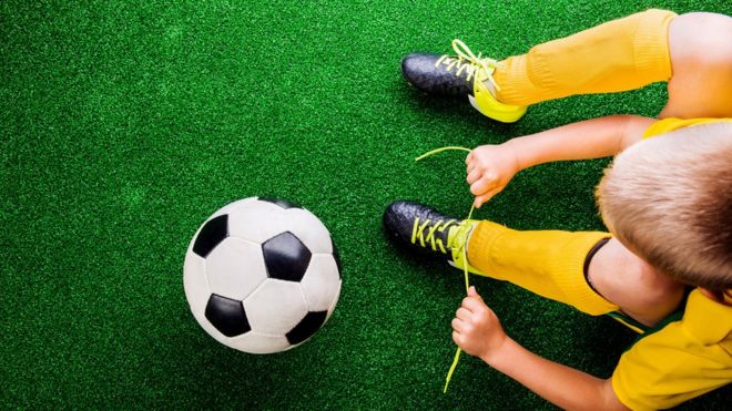 Мальчик и футбол на искусственном газоне