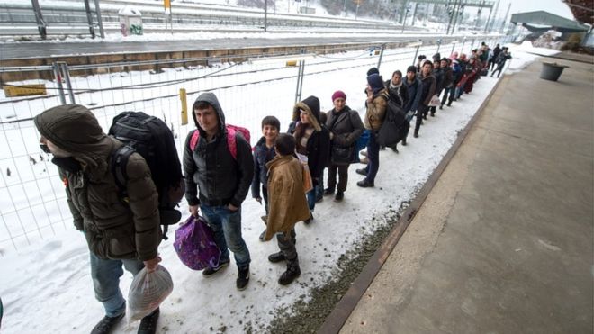 Refugees walk to a chartered train at the railway station of Passau, Germany, on 5 January 2016