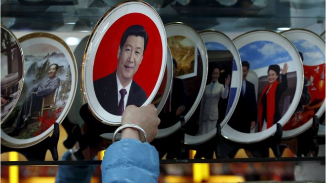 Продавец кладет сувенирную тарелку с изображениями президента Китая Си Цзиньпина на полку в магазине возле Большого зала народа