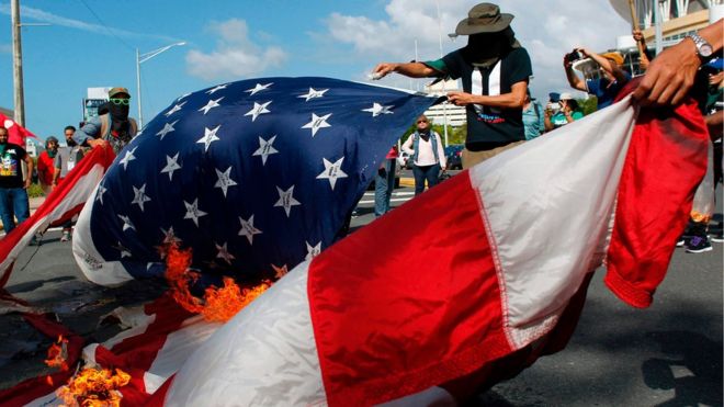 Протестующие сжигают СШАфлаг во время протеста против референдума за политический статус Пуэрто-Рико в Сан-Хуане, 11 июня 2017 года
