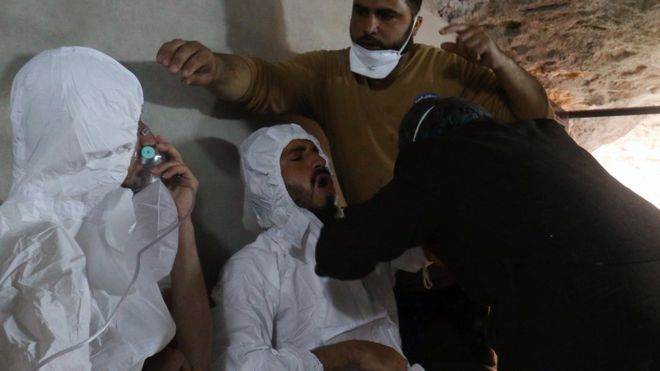 Мужчина дышит через кислородную маску, а другой получает лечение после того, что спасатели назвали предполагаемым химическим нападением в городе Хан-Шейхун в удерживаемой повстанцами провинции Идлиб, Сирия (4 апреля 2017 года)