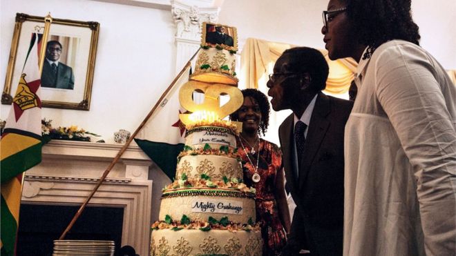 Президент Зимбабве Роберт Мугабе (C), в окружении своей жены Грейс Мугабе (слева) и дочери Боны (справа), задувает свечи на торте во время неожиданной вечеринки, организованной в офисе президента и кабинета в Государственном доме в Хараре, в феврале 22, 2016, чтобы отпраздновать свое 92-летие.