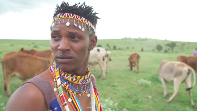Richard Turere with his goats in the background