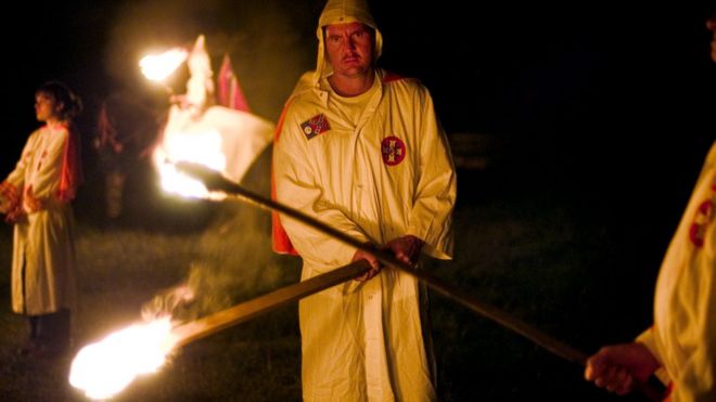 Участники Ku Klux Klan зажигают факелы, когда начинают церемонию перекрестного освещения на фестивале Дней Белого Наследия в Алабаме в 2004 году.