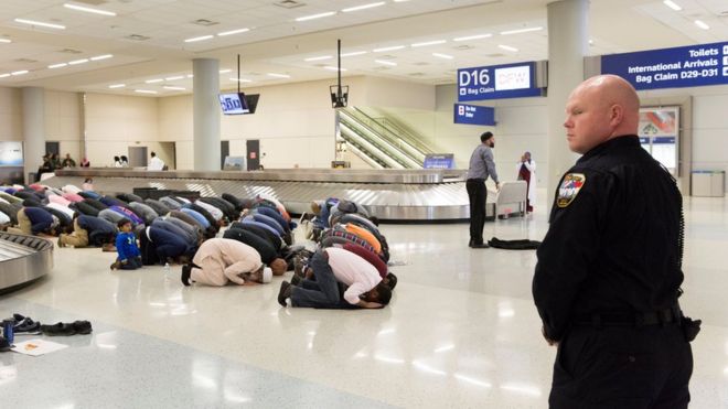 Люди собираются, чтобы помолиться в выдаче багажа во время протеста против запрета на поездки, наложенного указом президента США Дональда Трампа, в международном аэропорту Даллас / Форт-Уэрт в Далласе, штат Техас, США, 29 января 2017 года