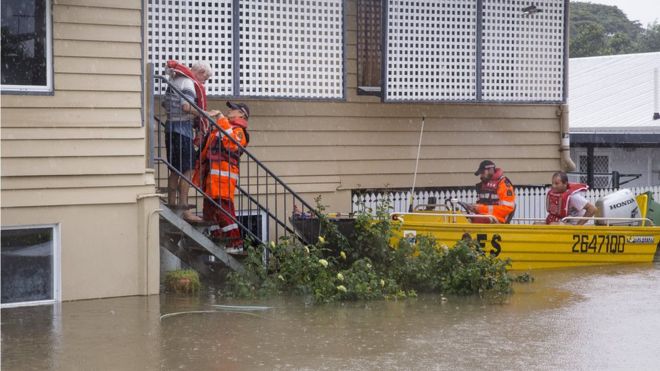 Аварийные работники в лодке помогают спасти пожилого жителя из его дома в Росслее, Таунсвилл