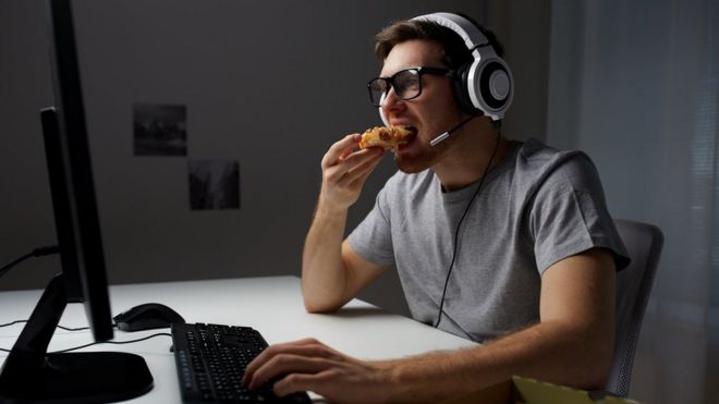 Мужчина ест пиццу за компьютером