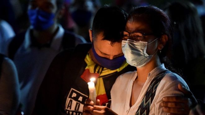 Padres de un muerto en las protestas de Colombia lloran durante una vigilia.