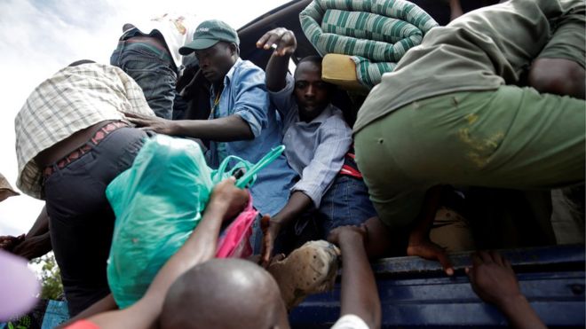Several men climbing onto the back of a packed lorry with their belongings after being released from a prison in in Bujumbura, Burundi.