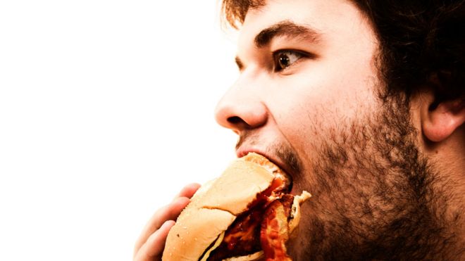Hombre engulliendo una hamburguesa