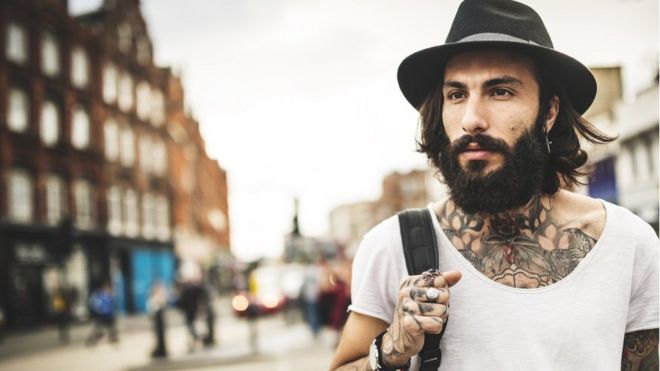 Un joven con tatuajes carga una mochila en Londres.