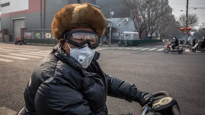 በቤይጂንግ ፊቱን በመተንፈሻ አካላት መከላከያ የሸፈነ ግለሰብ