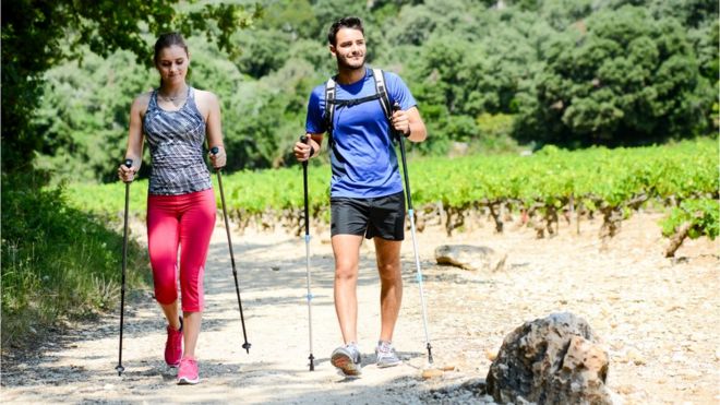 Pareja haciendo marcha nÃ³rdica en un paisaje natural.