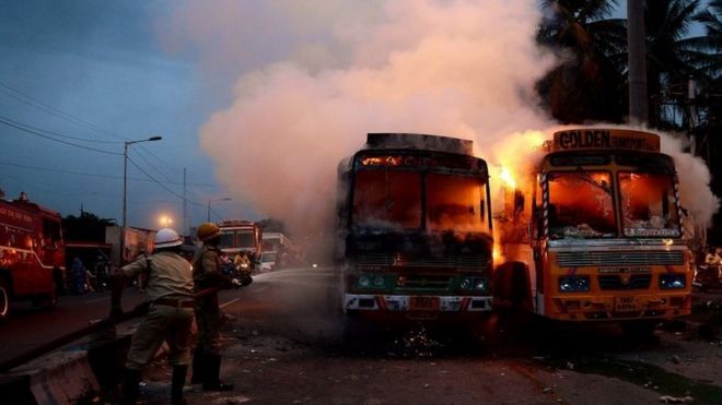 Индийские пожарные тушат грузовики, подожженные активистами про-Карнатаки (невидимыми) во время акции протеста в Бангалоре, Индия, 12 сентября 2016 года.