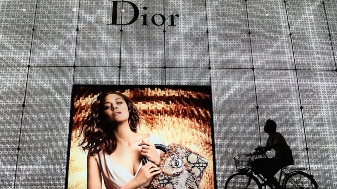 Китаец проезжает на велосипеде мимо рекламы магазина Christian Dior 8 июня 2012 г. в Пекине, Китай