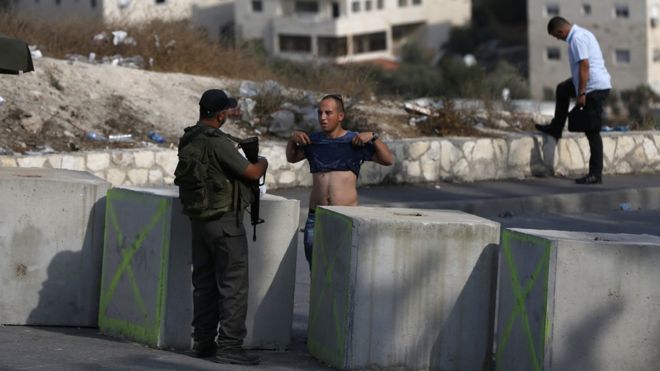 19 октября 2015 года израильский пограничник осматривает палестинца на недавно установленном контрольно-пропускном пункте на выезде из района Иссавия в восточном Иерусалиме